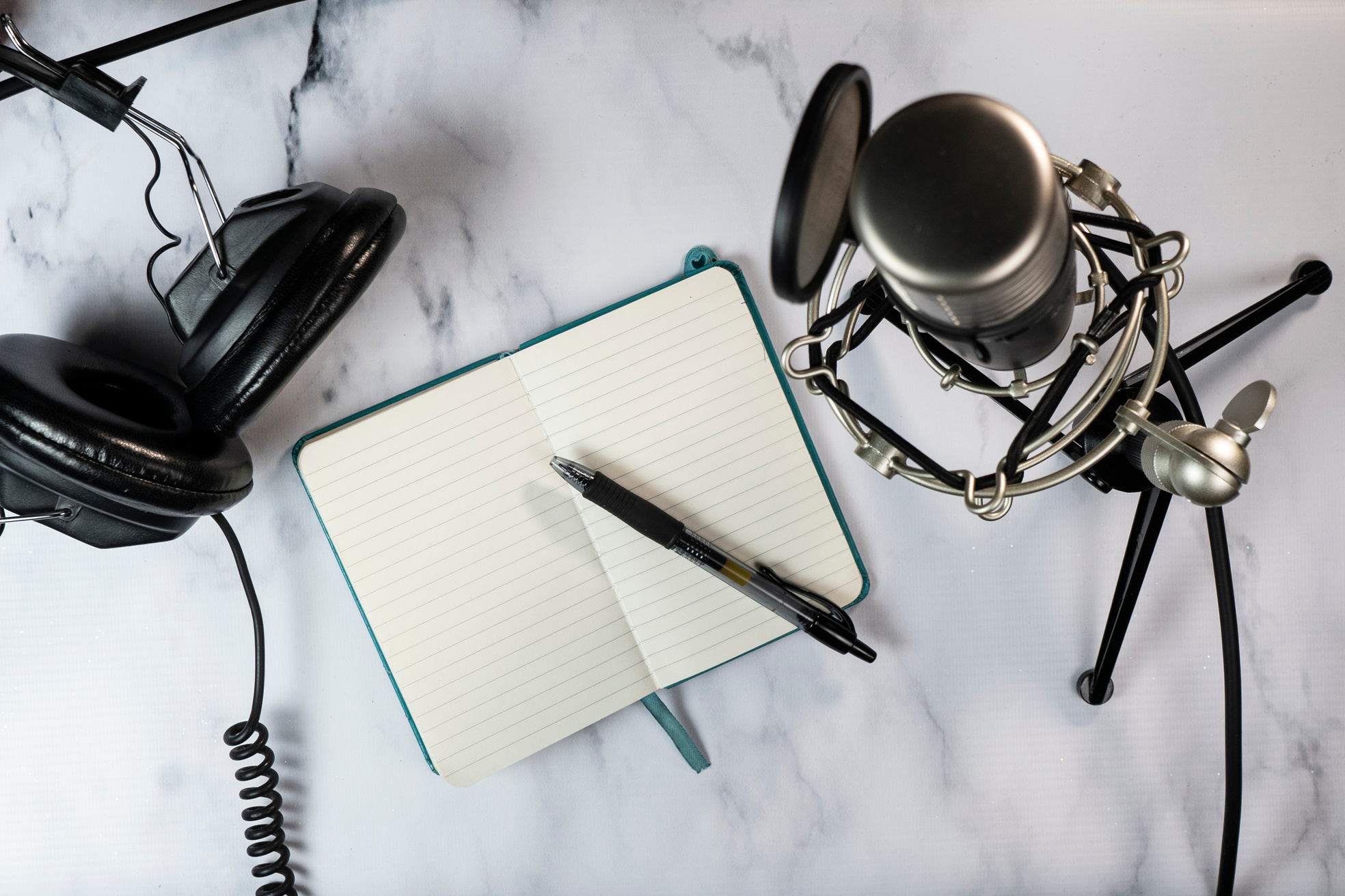 Flat lay of a podcast setting with microphone and notebook
